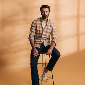 fit model sitting on a stool wearing The Jack in Baked Clay Plaid, Wovens by Taylor Stitch