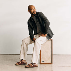 fit model sitting on a stereo wearing The Ojai Jacket in Faded Black Seersucker, Outerwear by Taylor Stitch