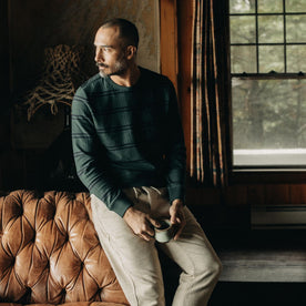 fit model leaning against a brown leather chair in The Colton Crew in Dark Forest Stripe, Knits by Taylor Stitch