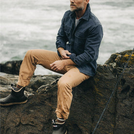 fit model sitting on a rock wearing The Democratic All Day Pant in Tobacco Selvage Denim, Bottoms by Taylor Stitch