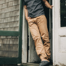 fit model leaning against the wall wearing The Democratic All Day Pant in Tobacco Selvage Denim, Bottoms by Taylor Stitch