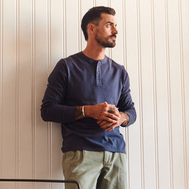 fit model leaning against the wall wearing The Organic Cotton Henley in Navy, Knits by Taylor Stitch