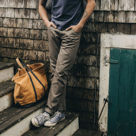 fit model leaning against the wall wearing The Slim All Day Pant in Fatigue Olive Selvage Denim, Bottoms by Taylor Stitch