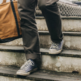 fit model walking down the stairs wearing The Slim All Day Pant in Fatigue Olive Selvage Denim, Bottoms by Taylor Stitch