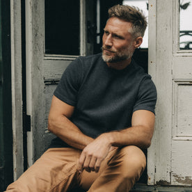 fit model sitting wearing The Heavy Bag Waffle Short Sleeve in Faded Black, Knits by Taylor Stitch