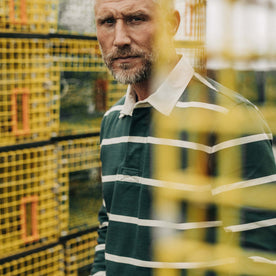 fit model looking through fishing boxes wearing The Rugby in Dark Forest Stripe, Knits by Taylor Stitch