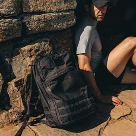 fit model sitting next to The GR1 USA in Raindrop Camo Ripstop WashWax, Accessories by Taylor Stitch