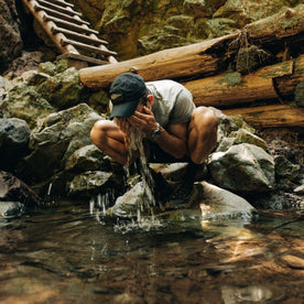 fit model splashing water on his face wearing The Performance TAC Hat in Black, Accessories by Taylor Stitch