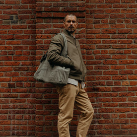 fit model leaning against the wall wearing The Foundation Tote in Organic Smoked Olive, Accessories by Taylor Stitch