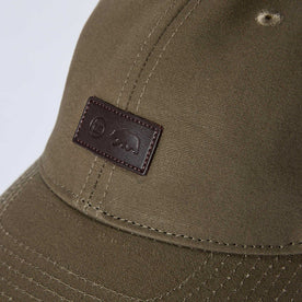 editorial image of the front tag on The Pathfinder Cap in Fatique Olive Dry Wax, Accessories by Taylor Stitch