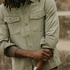 fit model adjusting the cuffs on The Surplus Shirt in Field Olive Reverse Sateen, Wovens by Taylor Stitch