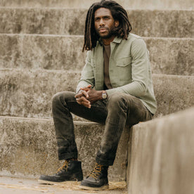 fit model sitting wearing The Surplus Shirt in Field Olive Reverse Sateen, Wovens by Taylor Stitch