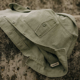 editorial image of The Surplus Shirt in Field Olive Reverse Sateen on a rock, Wovens by Taylor Stitch