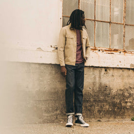 fit model leaning against the wall wearing The Surplus Shirt in Khaki Reverse Sateen, Wovens by Taylor Stitch