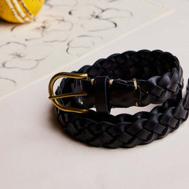 editorial image of The Braided Belt in Black rolled up on paper, Accessories by Taylor Stitch