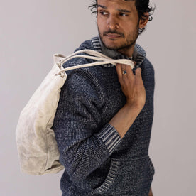 fit model with a bag over his shoulder wearing The Headland Pullover Sweater in Marled Navy, Knits by Taylor Stitch