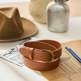 editorial image of The Foundation Belt in Whiskey rolled up on paper, Accessories by Taylor Stitch