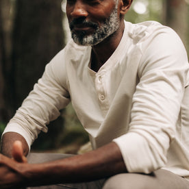 fit model sitting wearing The Heavy Bag Henley in Natural, Knits by Taylor Stitch