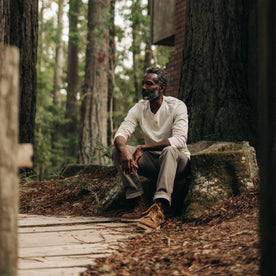 fit model sitting on a log in The Heavy Bag Henley in Natural, Knits by Taylor Stitch