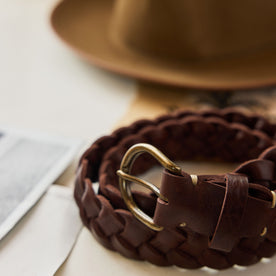 editorial image of The Braided Belt in Dark Brown rolled up on a piece of paper, Accessories by Taylor Stitch