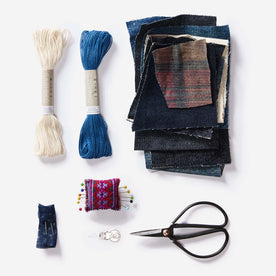 The thread, recycled denim patches, ashiko needles, pins and cushion and needle threader in the Sashiko Denim Repair Kit, Accessories by Taylor Stitch