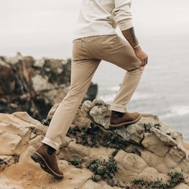 fit model walking on rocks in The Slim All Day Pant in Light Khaki Broken Twill, Bottoms by Taylor Stitch