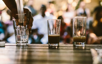 Brown water in the first of three glasses being tested for quality.