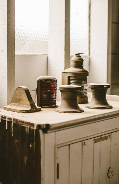 A white-painted sideboard with old brass lights and winches on top.