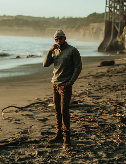 Our guy in fleece and workwear pants stadning on the beach, looks chilly!