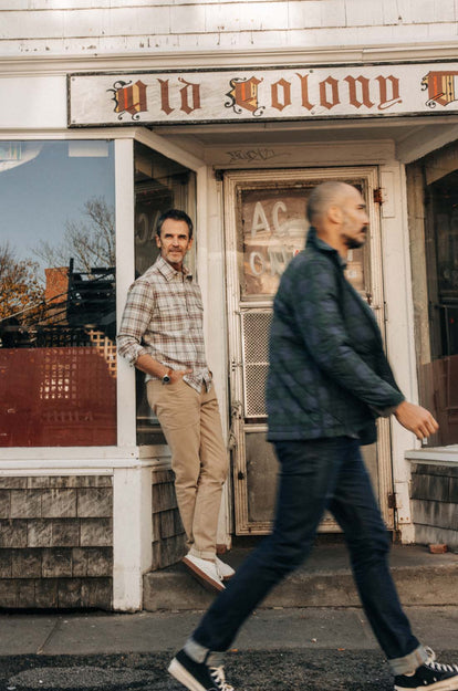 Model standing outside a store, wearing The Ledge Shirt in Redwood Plaid