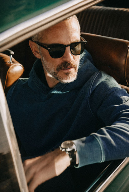 Model sitting in a car, wearing The Apres Hoodie in Washed Indigo Terry