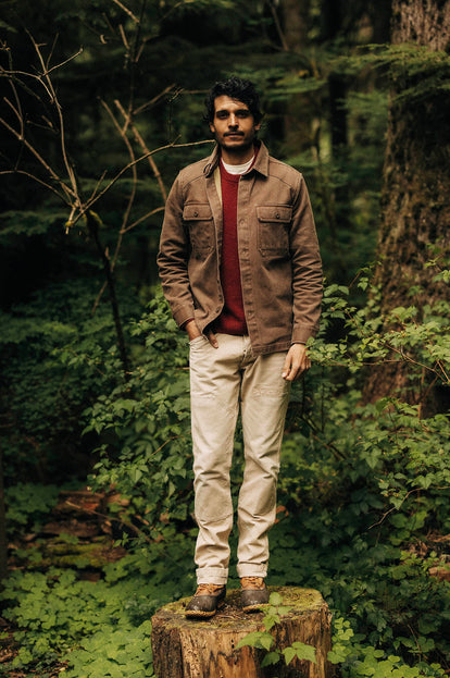 Model wearing The Shop Shirt in Aged Penny Chipped Canvas while standing on top of a log