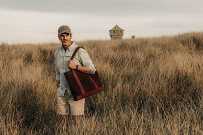 Model wearing an oxford shirt, holding a suede tote bag