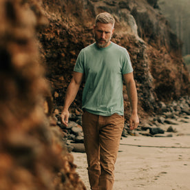 fit model walking along the Rocky Coast in The Cotton Hemp Tee in Teal, Knits by Taylor Stitch