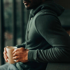 fit model sitting with a cup of coffee in The Fillmore Snap Hoodie in Deep Sea Terry, Knits by Taylor Stitch