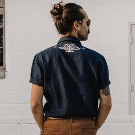 fit model facing the back in The Embroidered Short Sleeve Western in Indigo Linen, Wovens by Taylor Stitch