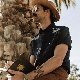 fit model writing in his sketchbook in The Embroidered Short Sleeve Western in Indigo Linen, Wovens by Taylor Stitch