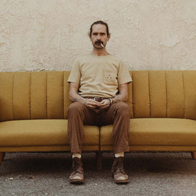 fit model sitting on a vintage couch in The Heavy Bag Tee in Khaki Dahlia, Knits by Taylor Stitch