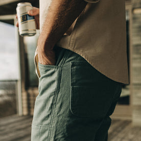 fit model wearing The Chore Pant in Ocean Boss Duck while holding a beer, Bottoms by Taylor Stitch