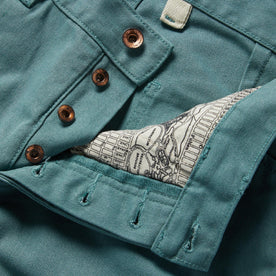 material shot of the buttons and map pocket printing on The Chore Pant in Ocean Boss Duck, Bottoms by Taylor Stitch