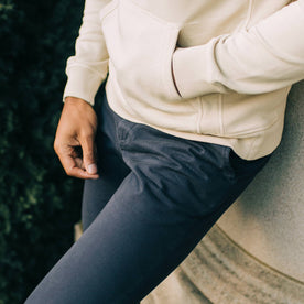 fit model leaning against a column in The Slim Foundation Pant in Dark Navy, Bottoms by Taylor Stitch