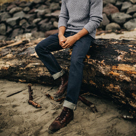 fit model on a log wearing The Slim Jean in Rinsed Organic Selvage, Bottoms by Taylor Stitch