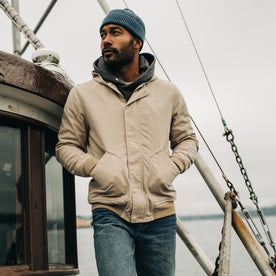 fit model standing on a boat with his hands in the pockets of The Workhorse Hoodie in Sand Boss Duck, Outerwear by Taylor Stitch