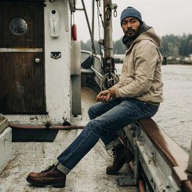 fit model sitting on the edge of a boat in The Workhorse Hoodie in Sand Boss Duck, Outerwear by Taylor Stitch