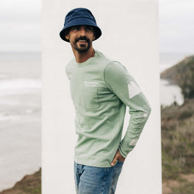 fit model standing in front of the sea in The Heavy Bag Long Sleeve in Party Wave, Knits by Taylor Stitch