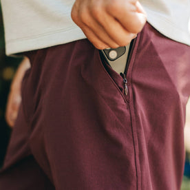 fit model wearing The Traverse Short in Wine, putting phone in pocket, Shorts by Taylor Stitch