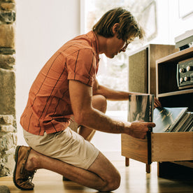 fit model looking through records in The Short Sleeve Hawthorne in Rust Stripe , Wovens by Taylor Stitch