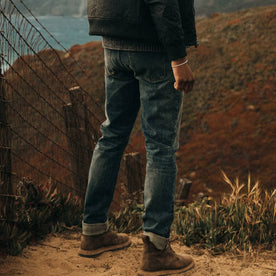 fit model wearing The Democratic Jean in in 18 Month Wash Organic Selvage, standing in dirt, Bottoms by Taylor Stitch