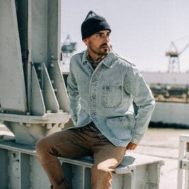 fit model wearing The Ojai Jacket in Washed Denim, sitting, looking right, Outerwear by Taylor Stitch