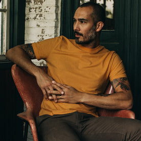 fit model sitting in The Cotton Hemp Tee in Mustard, Knits by Taylor Stitch